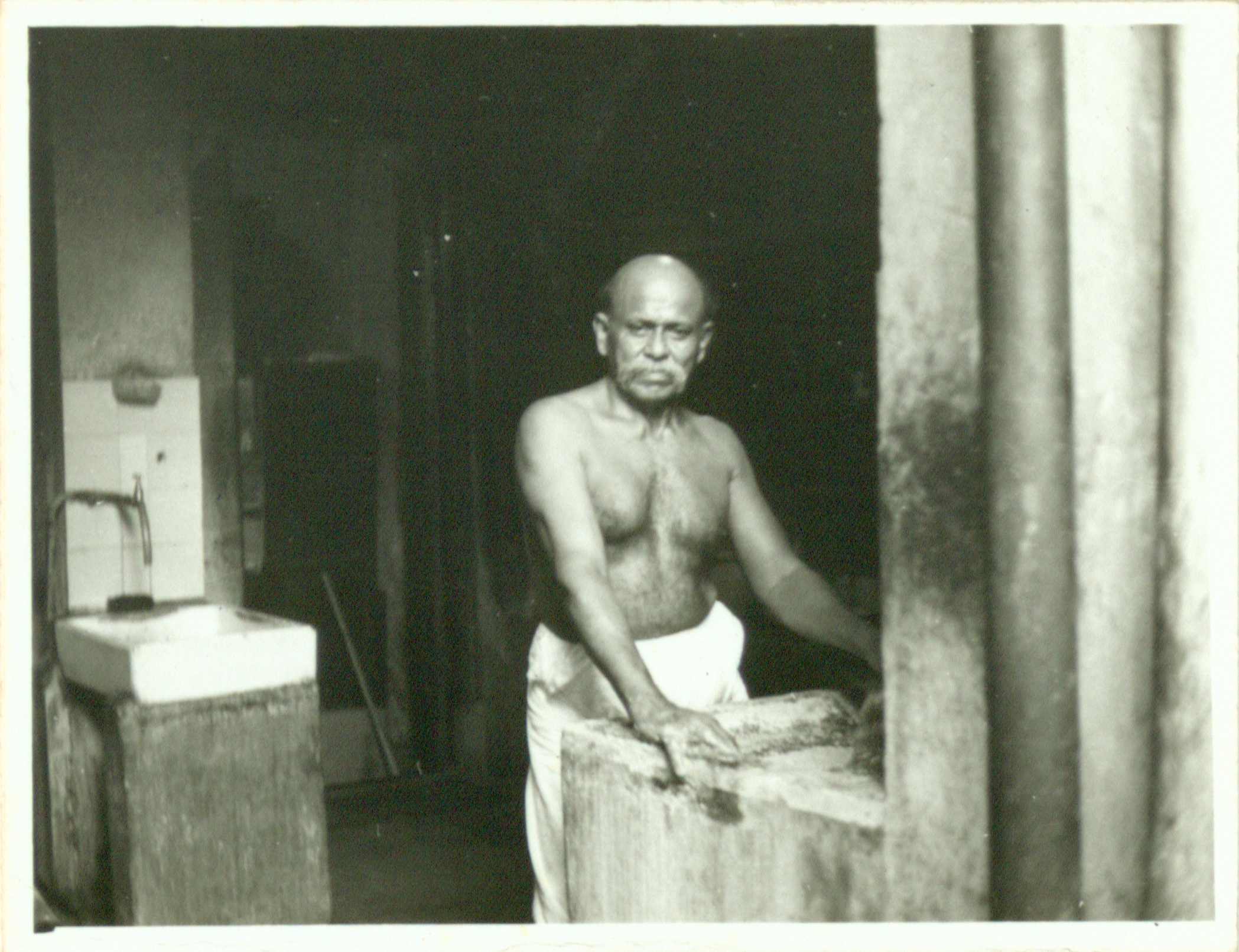 A cook grinding some spices at the cooking area inside the 49 Market Street Kittengi, 1970. Nachiappa Chettiar Collection, courtesy of National Archives of Singapore